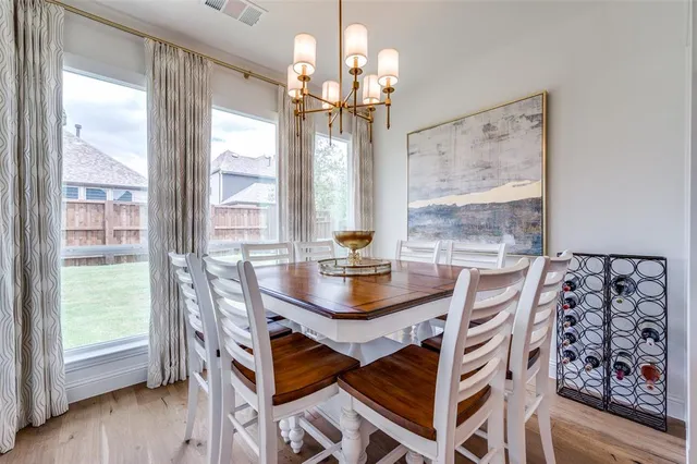 a dining room with wooden floor a chandelier a wooden table and chairs