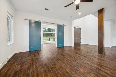 a view of an empty room with wooden floor and a window