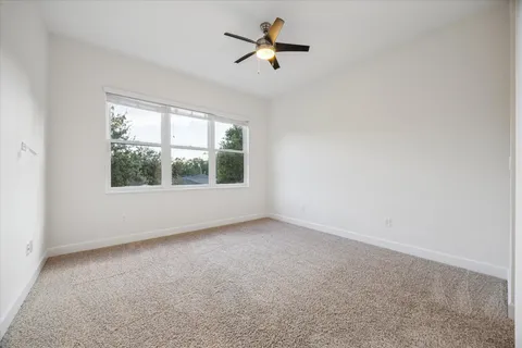 an empty room with a window and a ceiling fan