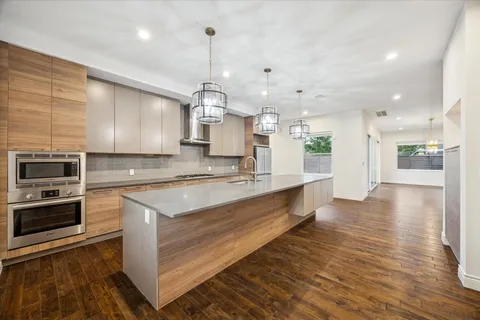 a large kitchen with stainless steel appliances kitchen island granite countertop a large counter top a stove and a wooden floors