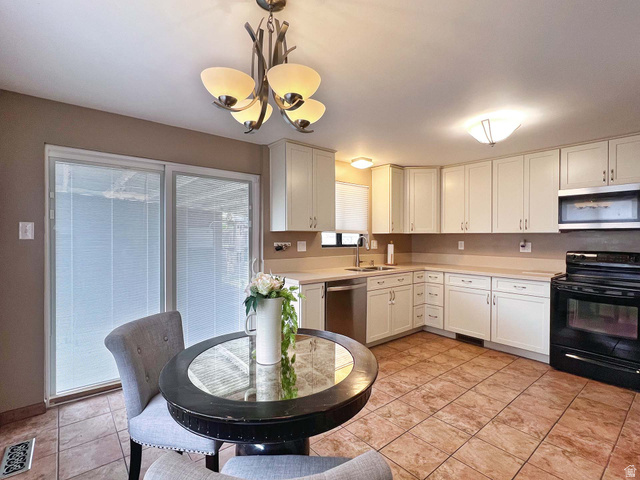 3138 Jean Street Magna, UT 84044 - Photo 9 of 26 Kitchen featuring an L-shaped counter, white cabinetry, integrated stainless steel dishwasher, tile flooring, and a sliding glass door