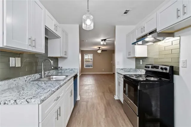 a kitchen with granite countertop a sink a counter space appliances and cabinets