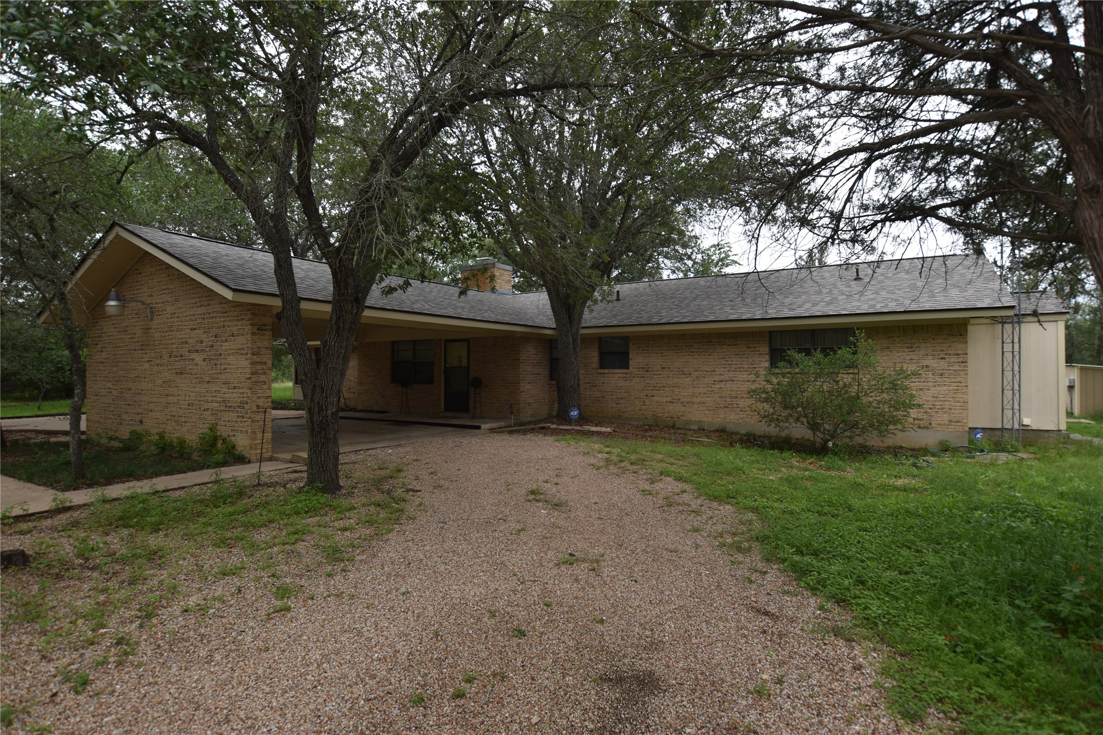 687 Fm 812 Road Red Rock, TX 78662 - Photo 1 of 40 Brick exterior residence featuring a covered carport, pitched shingle roof, and a gravel driveway
