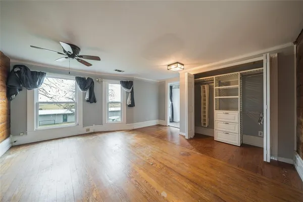 a view of an empty room with a window and wooden floor