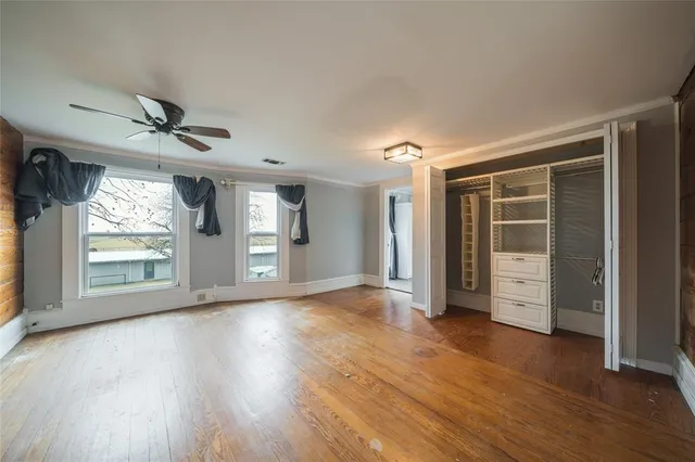 a view of an empty room with a window and wooden floor