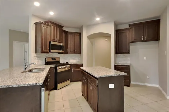 a kitchen with granite countertop stainless steel appliances a sink a counter top space cabinets and stainless steel appliances
