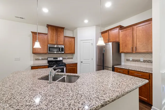 a kitchen with stainless steel appliances granite countertop a stove refrigerator sink and microwave
