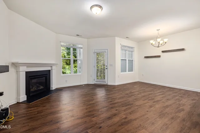 an empty room with wooden floor fireplace and windows