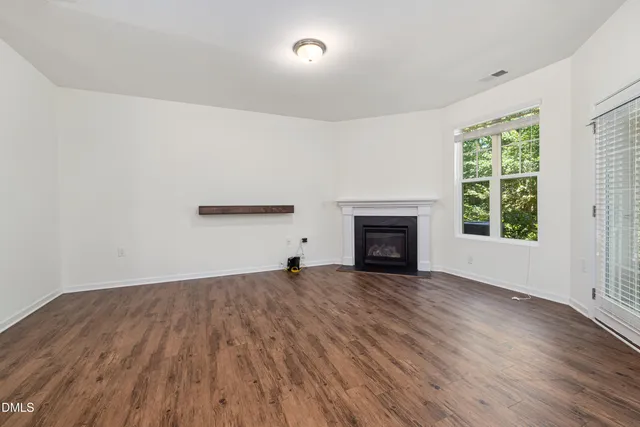 an empty room with wooden floor and fireplace