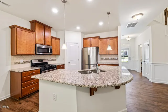 a kitchen with stainless steel appliances granite countertop a sink a stove and refrigerator