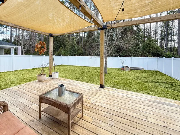 a view of a roof deck with wooden floor and fence next to a yard