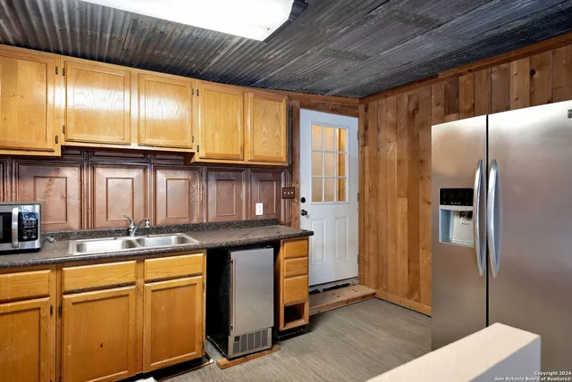 a kitchen with stainless steel appliances granite countertop a refrigerator a sink and wooden cabinets