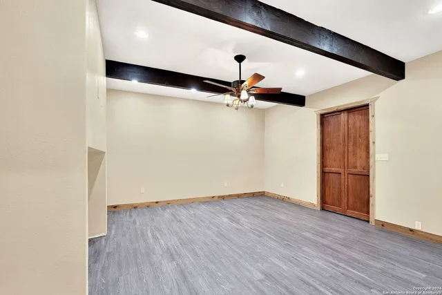 an empty room with wooden floor staircase and a ceiling fan