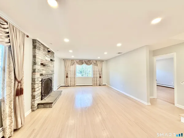 a view of an empty room with wooden floor and a window