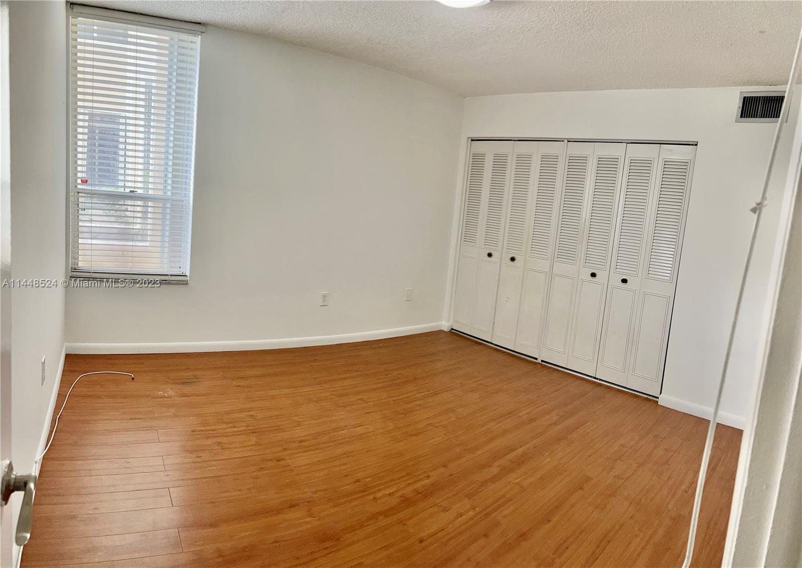 6801 Southwest 147th Avenue, Unit 1E2 Miami, FL 33193 - Photo 8 of 15 a view of an empty room with wooden floor and a window