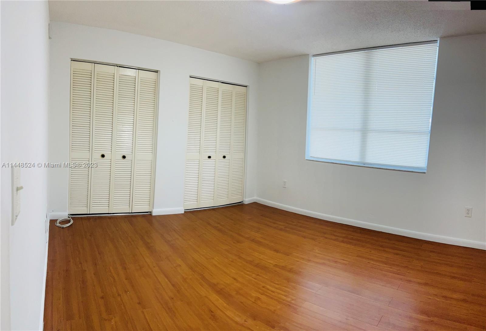 6801 Southwest 147th Avenue, Unit 1E2 Miami, FL 33193 - Photo 10 of 15 a view of an empty room with wooden floor and a window