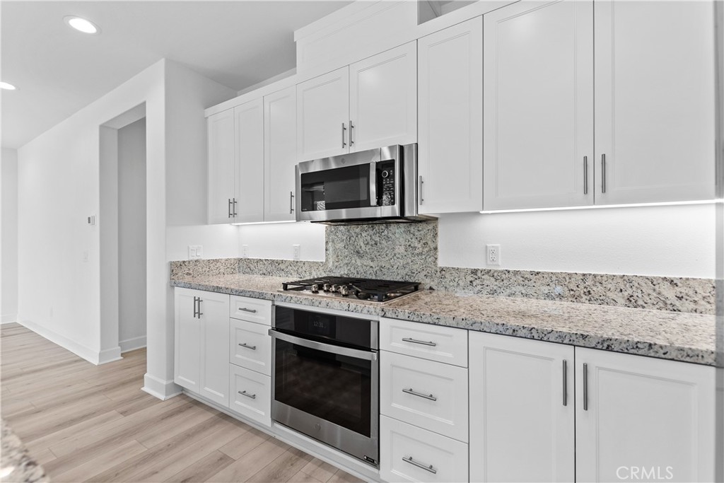 5024 Rexton Drive Camarillo, CA 93012 - Photo 11 of 48 a kitchen with granite countertop white cabinets and stainless steel appliances