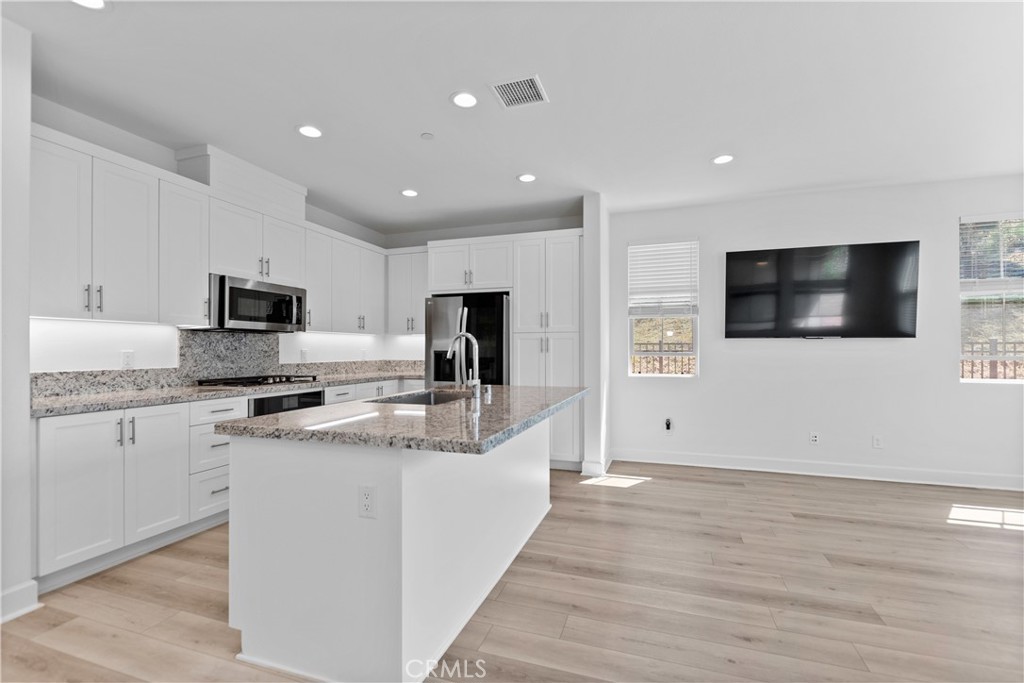 5024 Rexton Drive Camarillo, CA 93012 - Photo 12 of 48 a large white kitchen with stainless steel appliances granite countertop a stove a sink and a microwave