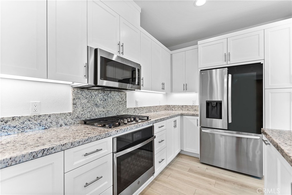 5024 Rexton Drive Camarillo, CA 93012 - Photo 9 of 48 a kitchen with granite countertop a refrigerator stove and microwave