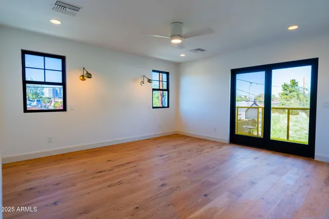a view of an empty room with a window and wooden floor