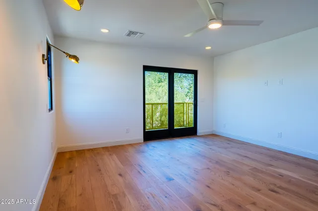 an empty room with wooden floor and windows