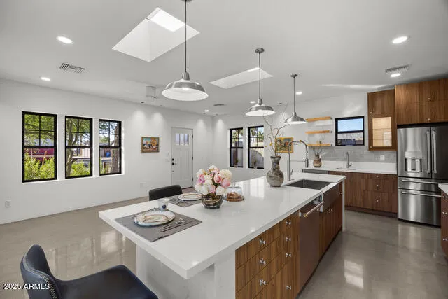 a kitchen with stainless steel appliances kitchen island granite countertop a sink a stove and a refrigerator