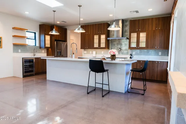 a kitchen with stainless steel appliances granite countertop a stove top oven a sink a dining table and chairs