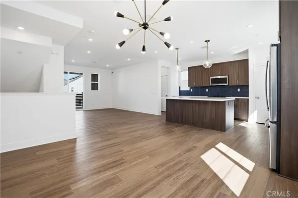 a kitchen with stainless steel appliances a refrigerator a sink cabinets and wooden floor