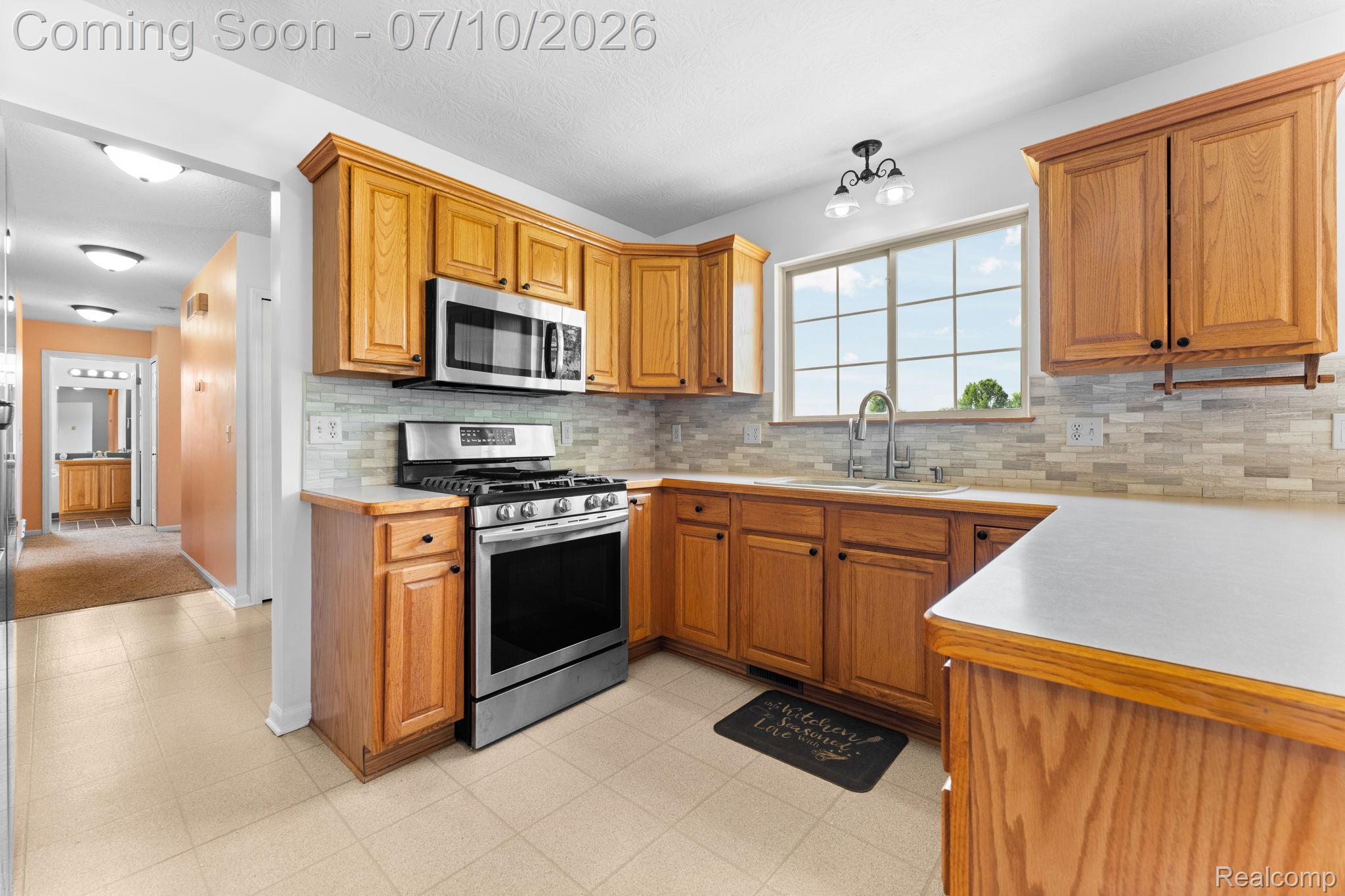 3144 North Nicholson Road Fowlerville, MI 48836 - Photo 40 of 70 Kitchen featuring wood cabinetry, stainless steel appliances, a tile backsplash, and a window above the sink