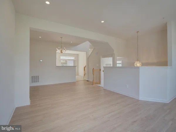 a view of an empty room with kitchen and window