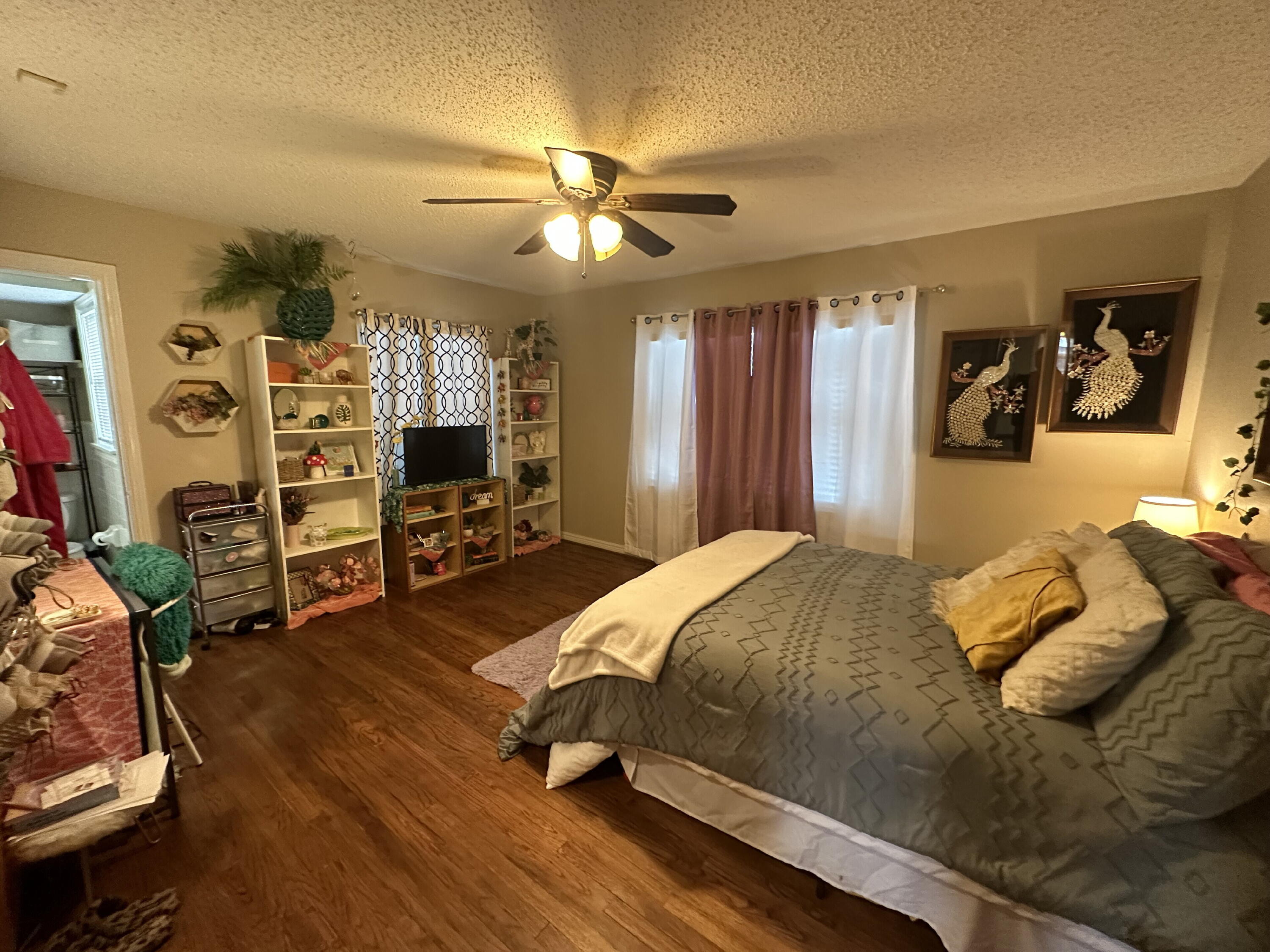 3214 32nd Street Lubbock, TX 79410 - Photo 9 of 17 a bedroom with a bed a ceiling fan and a flat tv screen on dresser