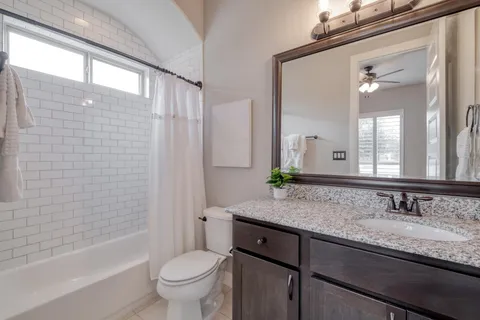 a bathroom with a granite countertop sink a toilet a mirror a vanity and bathtub