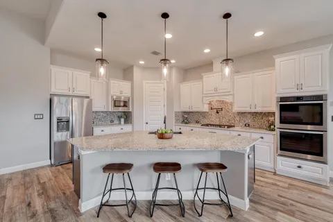a kitchen with stainless steel appliances kitchen island granite countertop a stove a sink and a refrigerator
