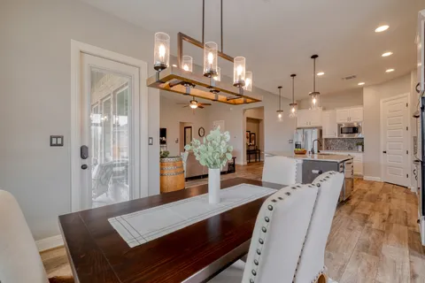 a view of a dining room and livingroom with furniture wooden floor a chandelier