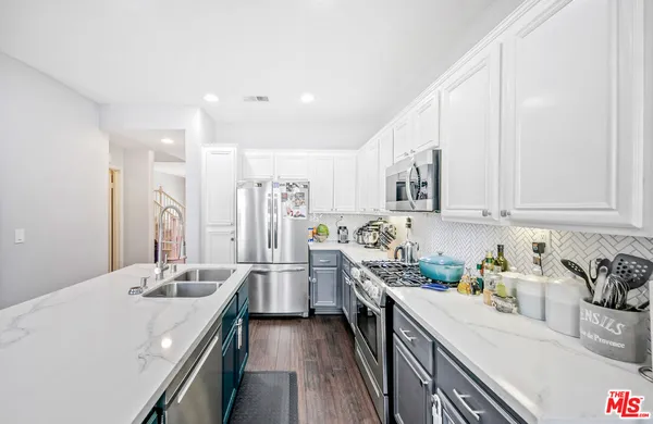 a kitchen with stainless steel appliances sink stove refrigerator and cabinets