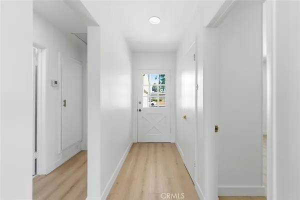 a view of a hallway with wooden floor and a bathroom