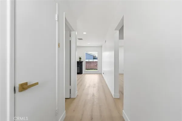 a view of a hallway with wooden floor and a bathroom