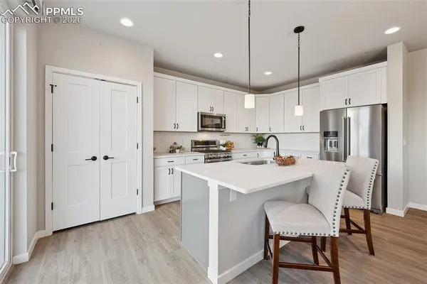 a kitchen with a refrigerator a stove a microwave oven a sink with island and wooden floor