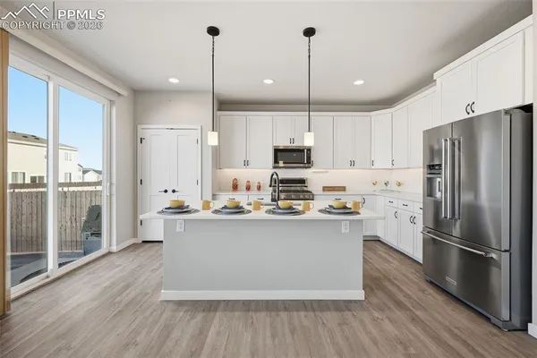 a kitchen with stainless steel appliances a refrigerator a stove a sink and white cabinets with wooden floor