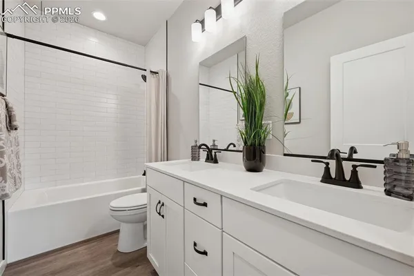 a bathroom with a double vanity sink a toilet and a tub