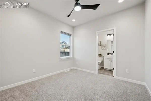 an empty room with a ceiling fan and carpet