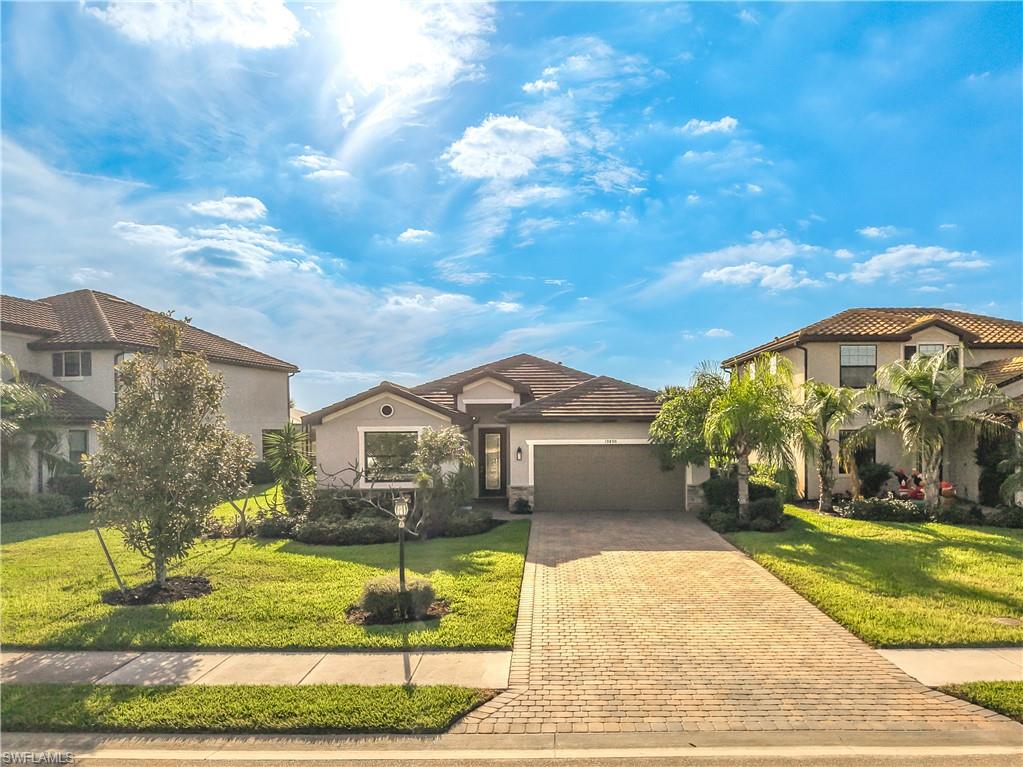 View of front of property with a front lawn, decorative driveway, and a garage