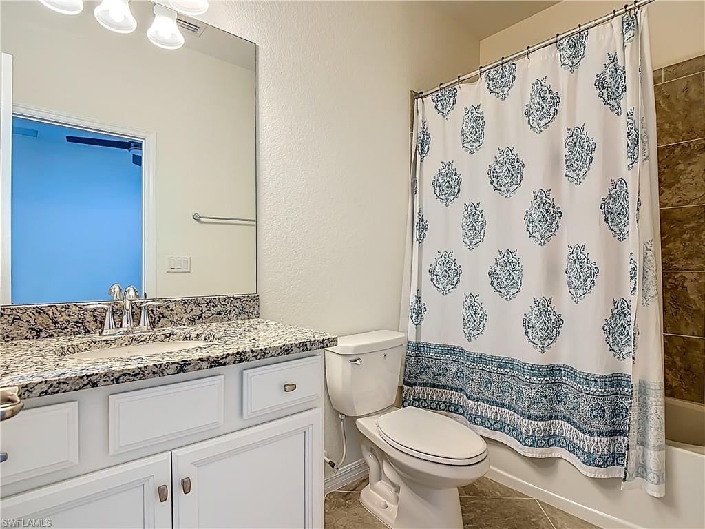 19890 Beverly Park Road Estero, FL 33928 - Photo 21 of 38 Bathroom with shower / bathtub combination with curtain, vanity, and light tile patterned floors