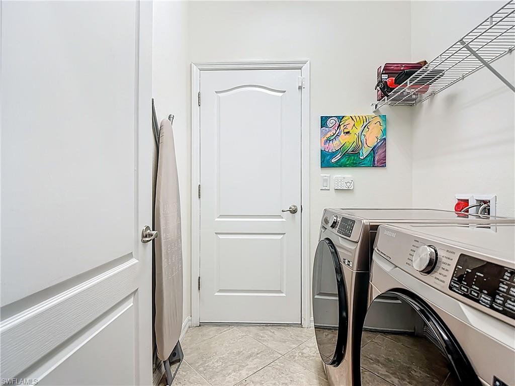 19890 Beverly Park Road Estero, FL 33928 - Photo 24 of 38 Laundry area featuring washer and dryer and light tile patterned flooring