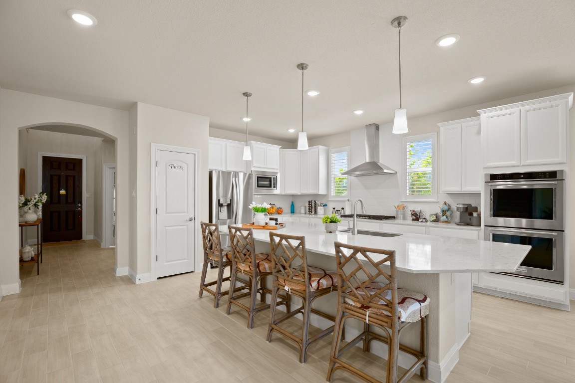 Delight in the spacious and well-appointed kitchen, featuring luxurious quartz countertops, white cabinetry, and stainless-steel appliances.