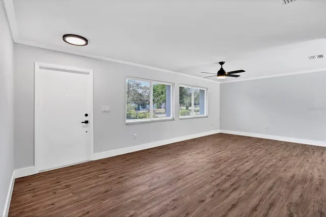 a view of an empty room with wooden floor and a window