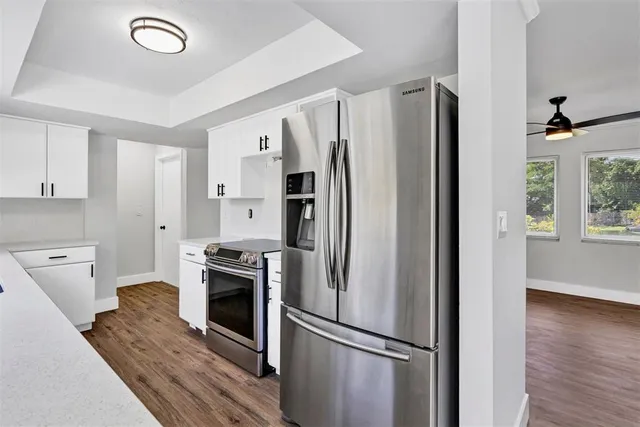 a kitchen with a refrigerator stainless steel appliances wooden floor and cabinets