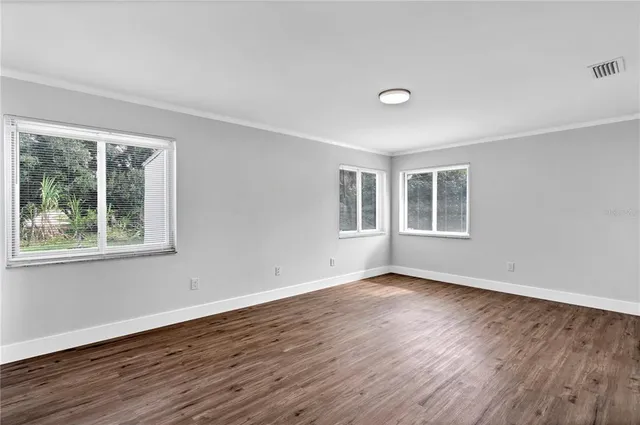 a view of empty room with wooden floor and fan