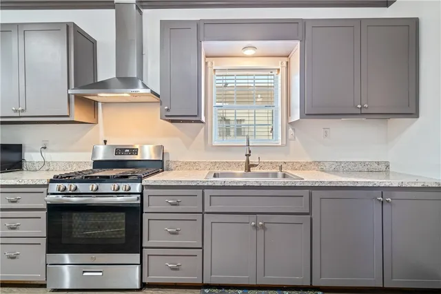 a kitchen with granite countertop a stove a sink and dishwasher wooden cabinets