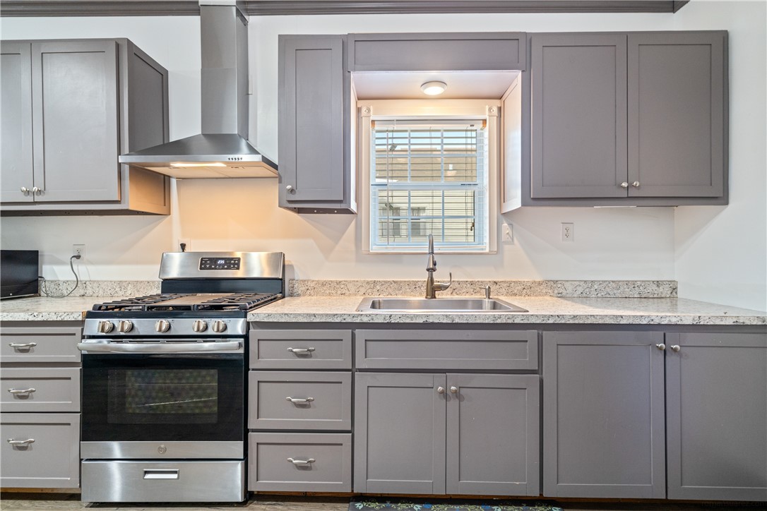 1205 10th Street Corpus Christi, TX 78404 - Photo 27 of 38 a kitchen with granite countertop a stove a sink and dishwasher wooden cabinets